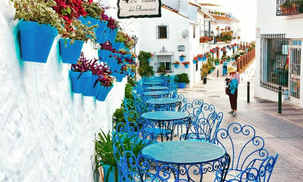 blue metal bistro sets near potted flowers and road