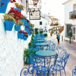 blue metal bistro sets near potted flowers and road