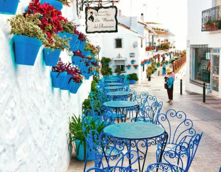 blue metal bistro sets near potted flowers and road