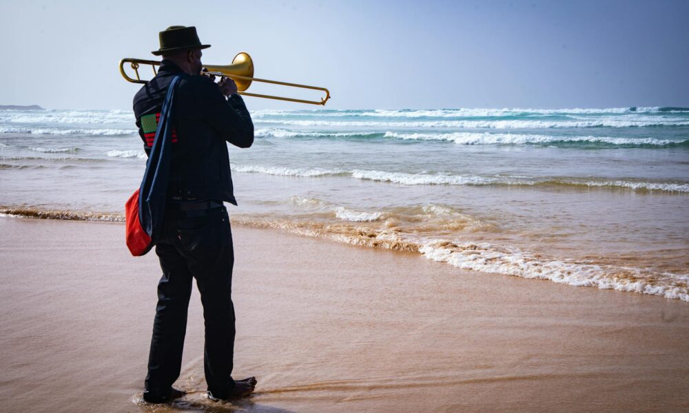 a man playing a trumpet on the beach