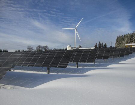 solar panels on snow with windmill under clear day sky