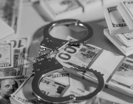 silver handcuffs on top of bundled paper money
